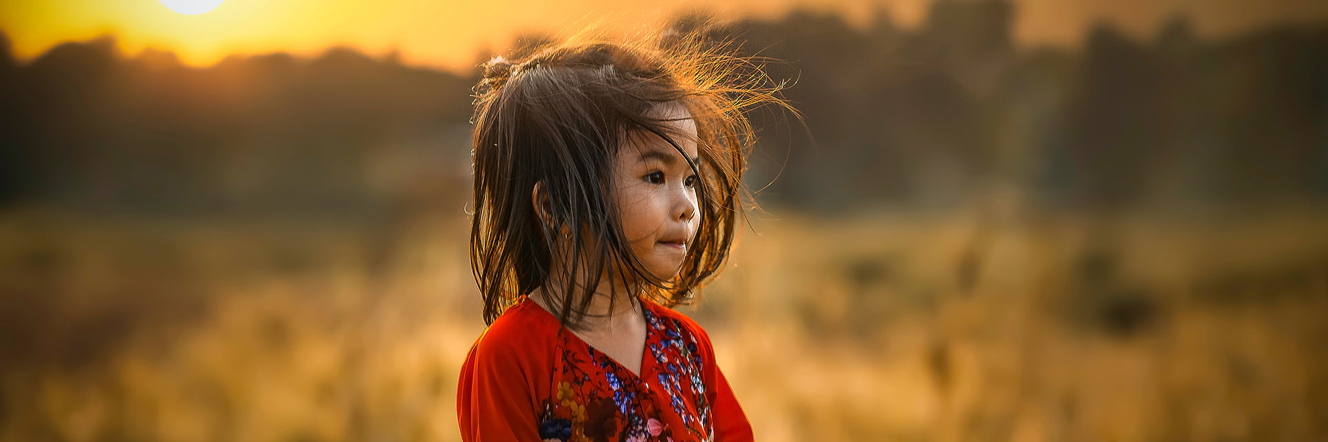 A little girl on a field during golden hour.
