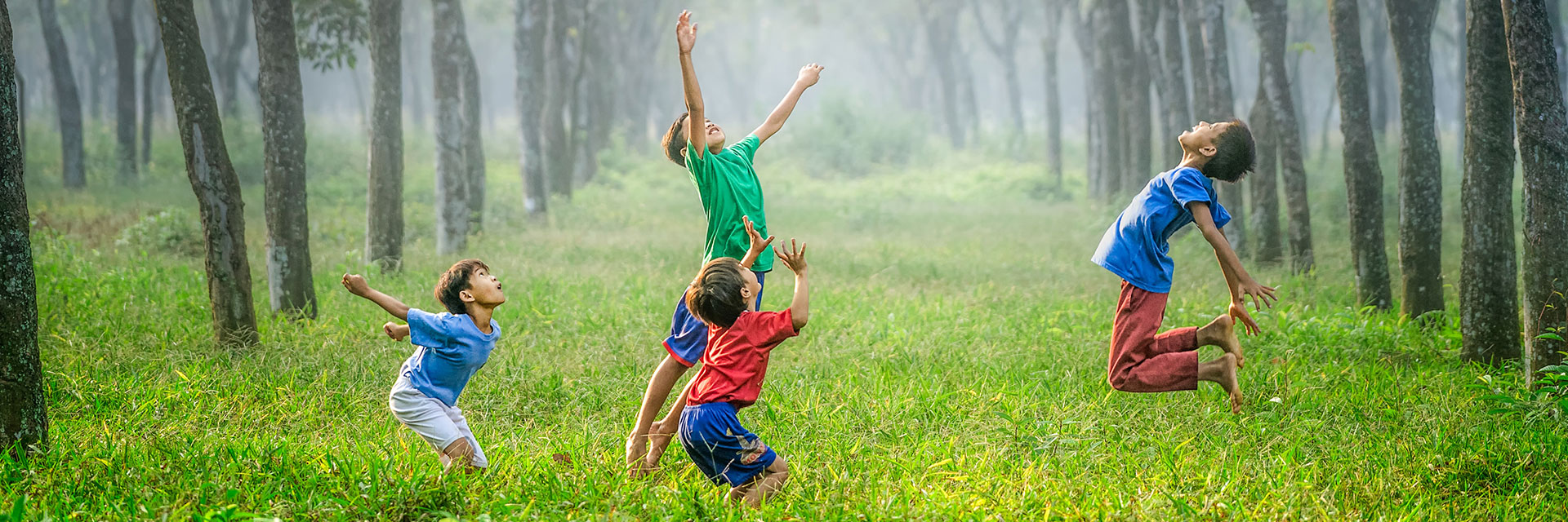 Four boys playing ball in green grass, Jakarta, Indonesia.