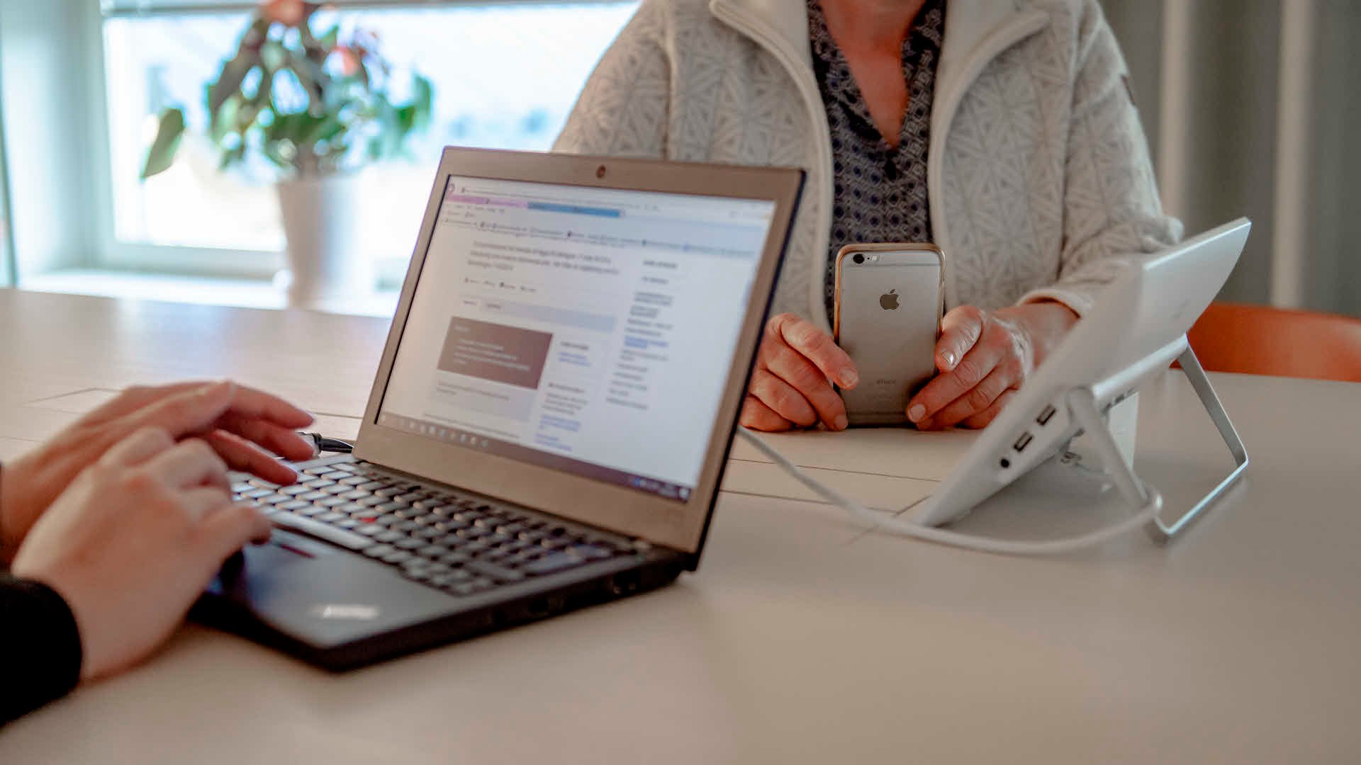 Fotograf: Naturvårdsverket Ett par händer på ett tangentbord, en person håller i en mobiltelefon.