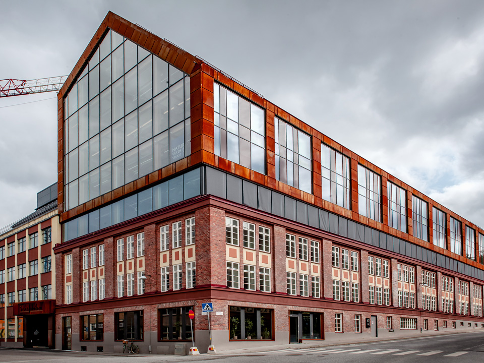 Naturvårdsverkets kontor i Hammarby sjöstad, Stockholm, fotograferat från gatan. I bakgrunden syns en molnig himmel. 