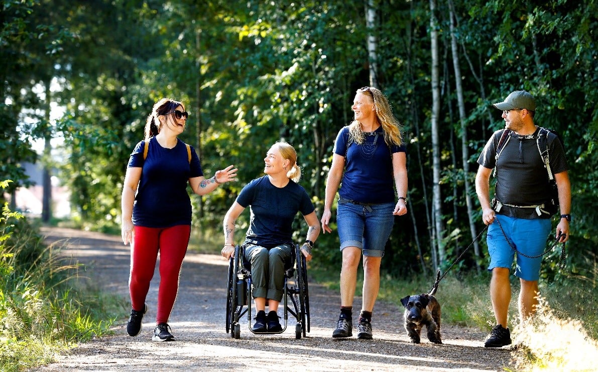 Fotograf: Karlstad kommun Fyra personer och en hund på en skogsväg.