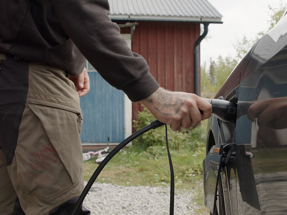 Närbild på en hand som kopplar in laddkabel i en bil