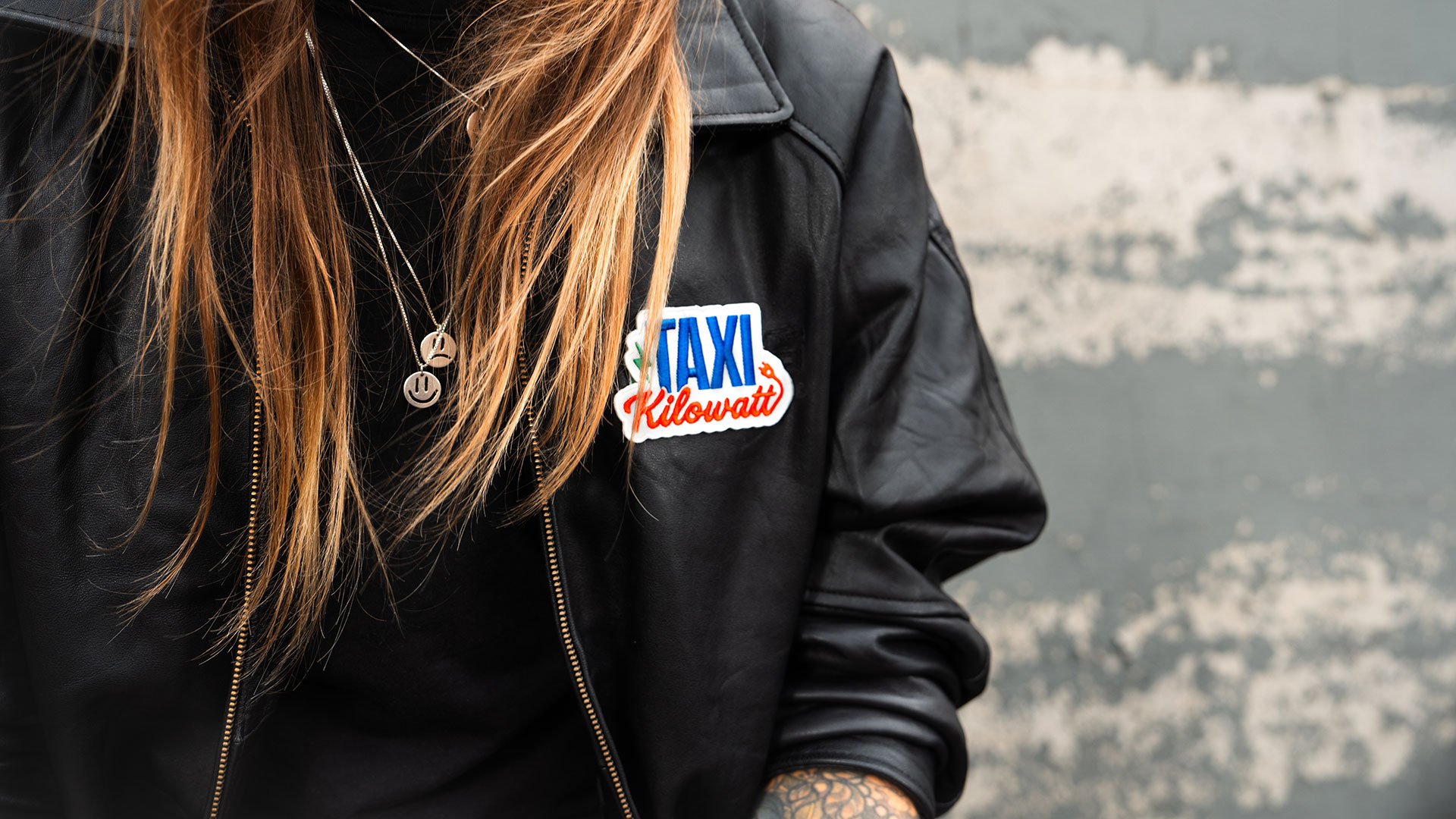 Närbild på en kvinna med Taxi kilowatt-logotyp på sin svarta skinnjacka