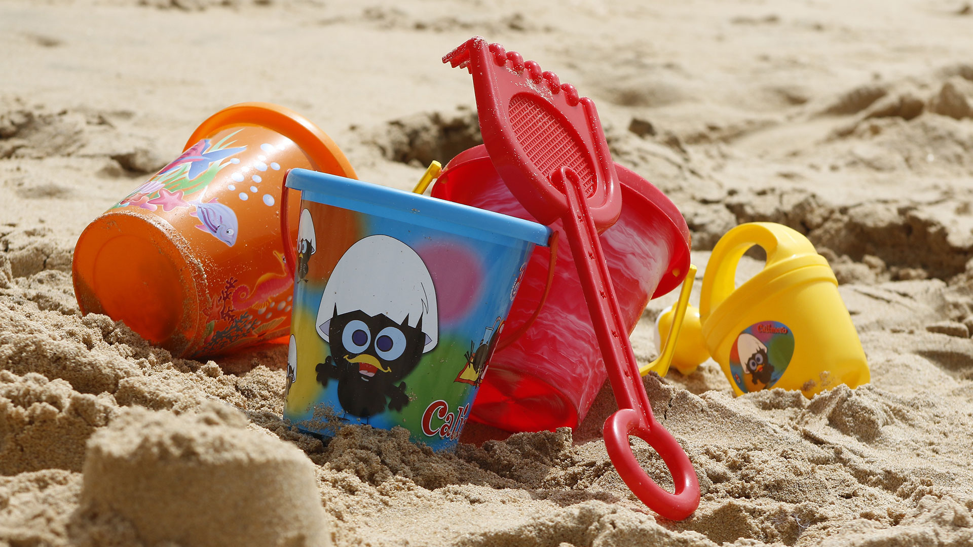 Plastleksaker på en sandstrand.