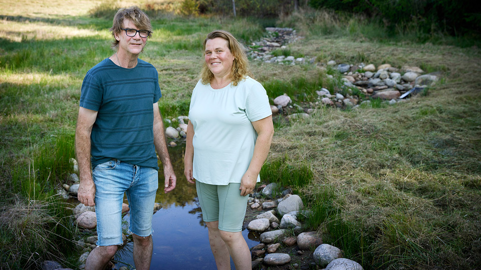 Fotograf: Anna-Lena Lundqvist Två personer står framför en slingrande bäck på äng