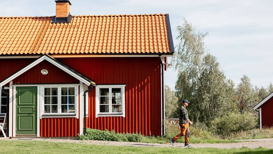 Fotograf: Lisa Öberg Rött hus med grön dörr och en man utanför