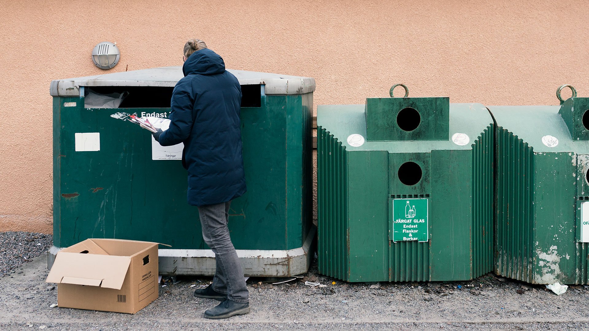 Sopsortering, man stoppar in tidningar.