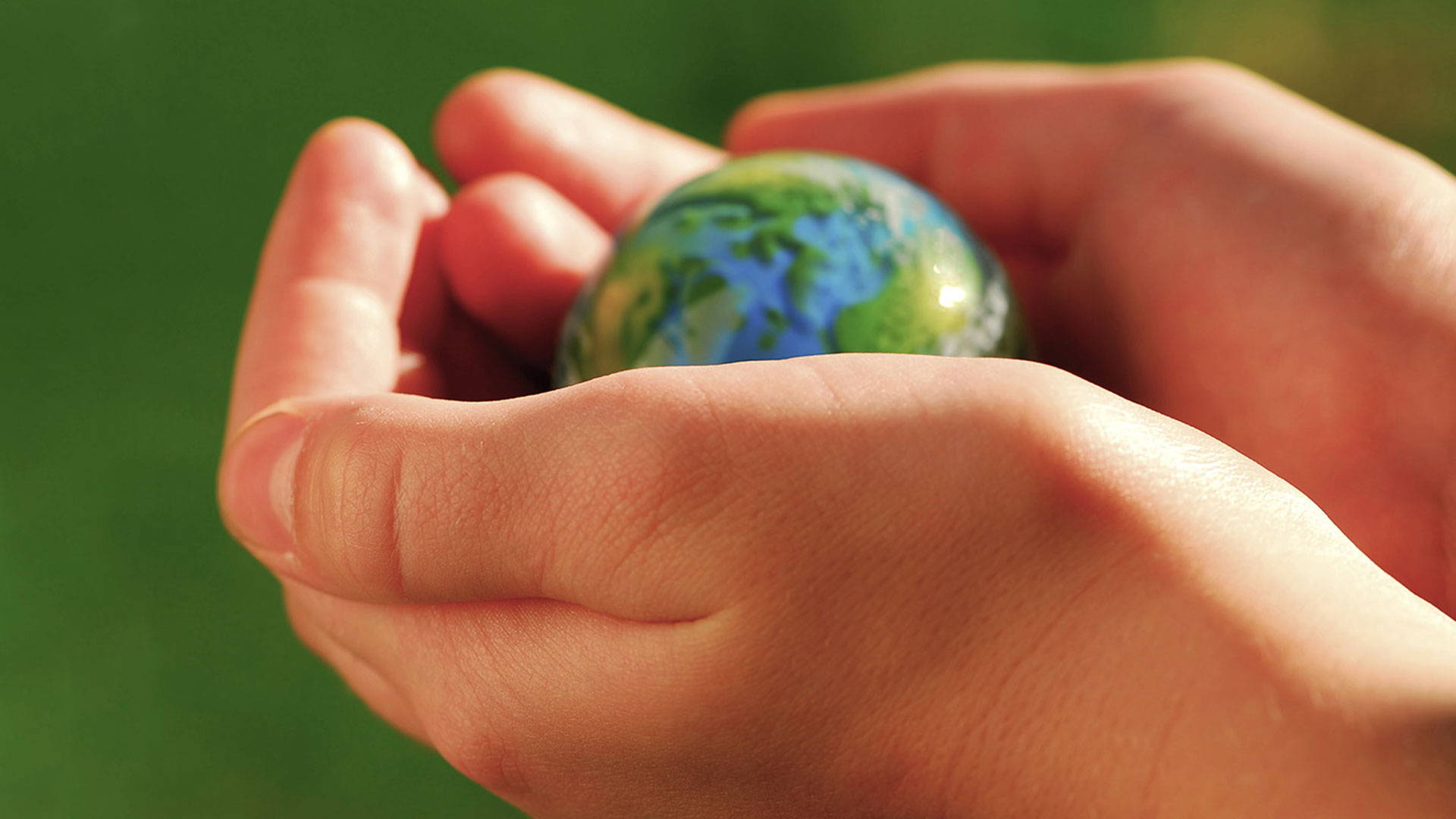 Händer som håller i en miniatyr av planeten jorden.