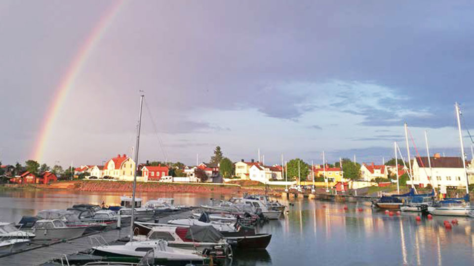 Regnbåge över en båthamn.