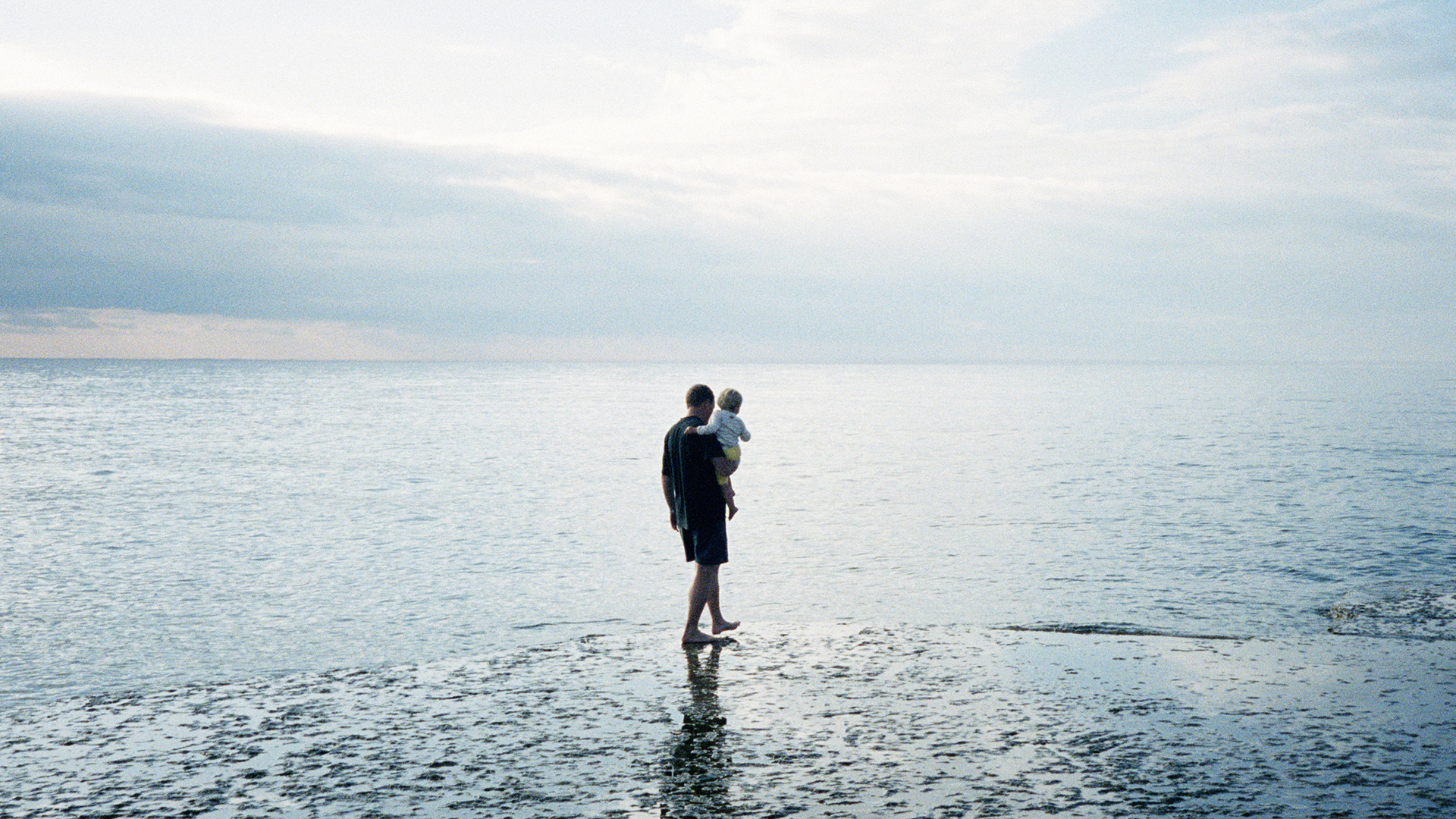 Pappa med barn går på klipphäll vid havet, Öland.