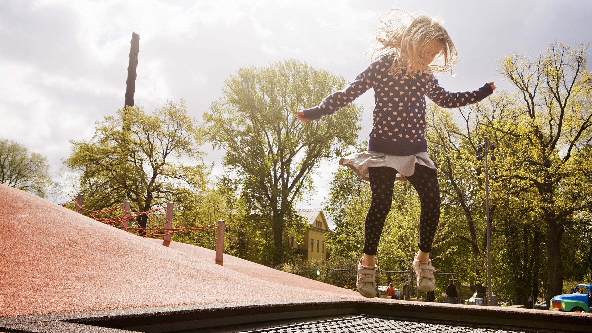 Flicka hoppar på en lekplats.