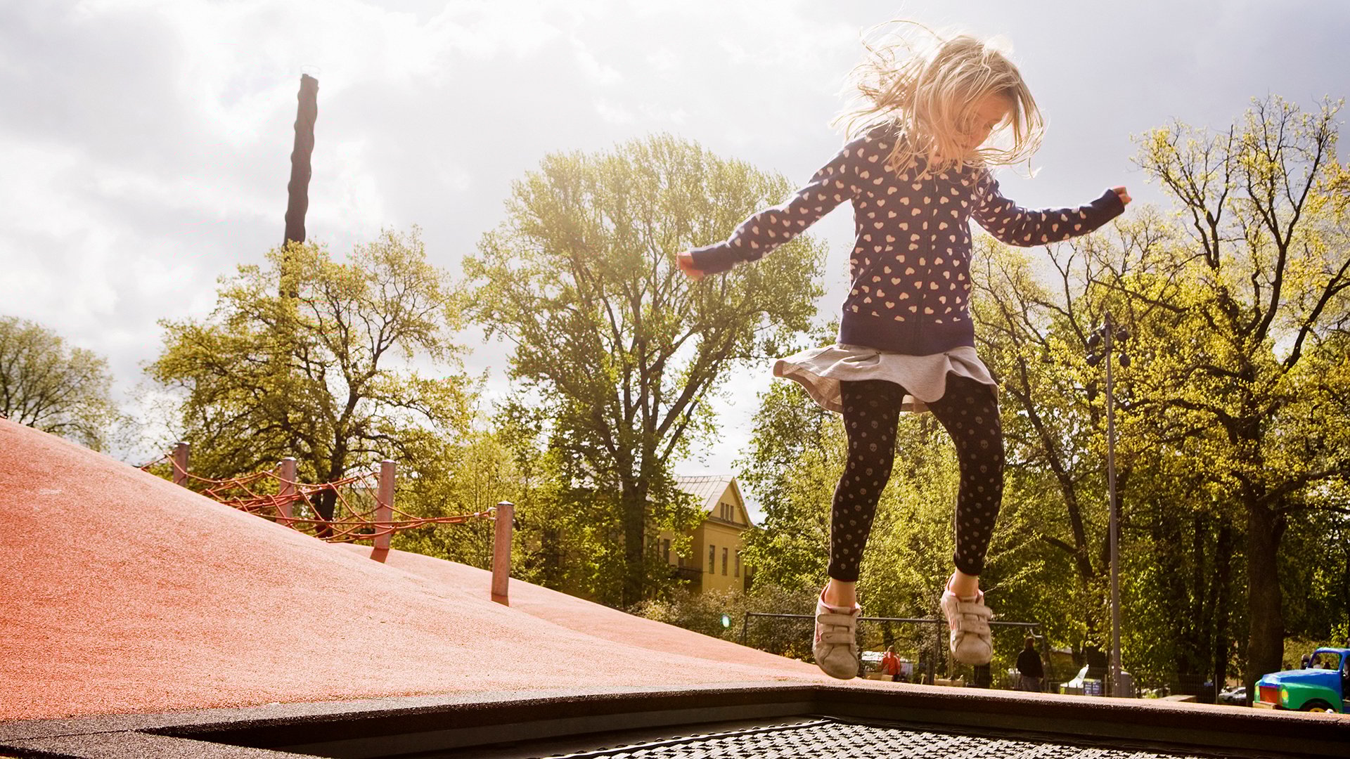 Fotograf: Susanne Kronholm. Flicka hoppar på en lekplats.